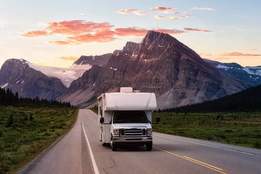 camper van driving on scenic highway with mountains in background